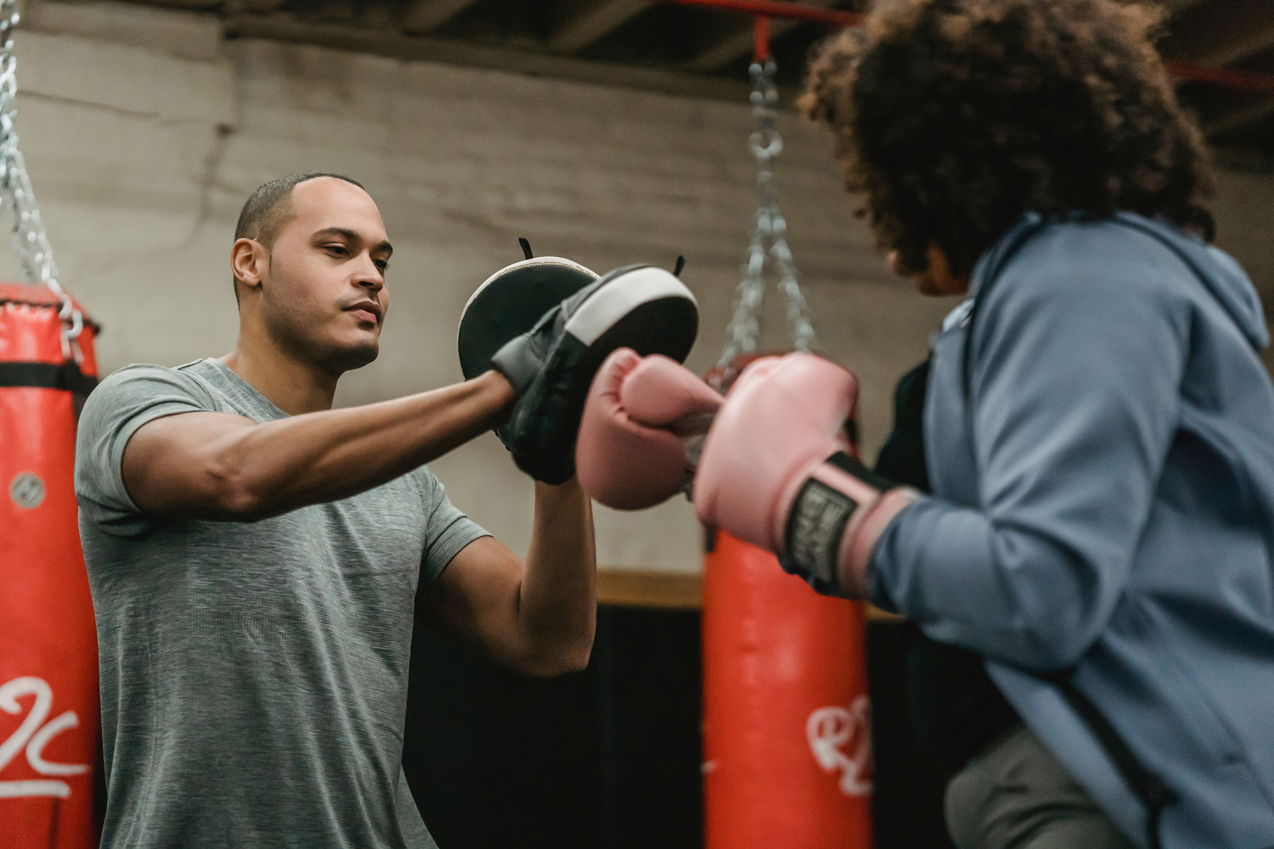 Personal black trainer boxing with unrecognizable woman